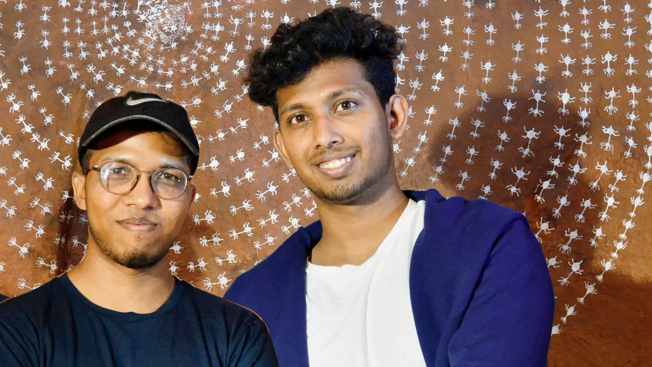 Mayur and Tushar Vayeda in front of one of their Warli paintings
